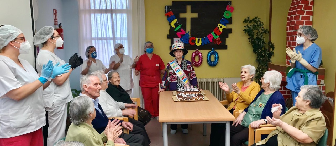 Cumpleaños de una persona mayor acompañada del personal sanitario y otros residentes