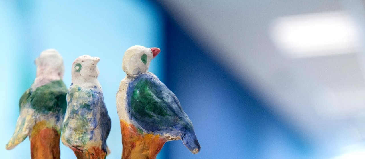 Escultura colorida de tres palomas