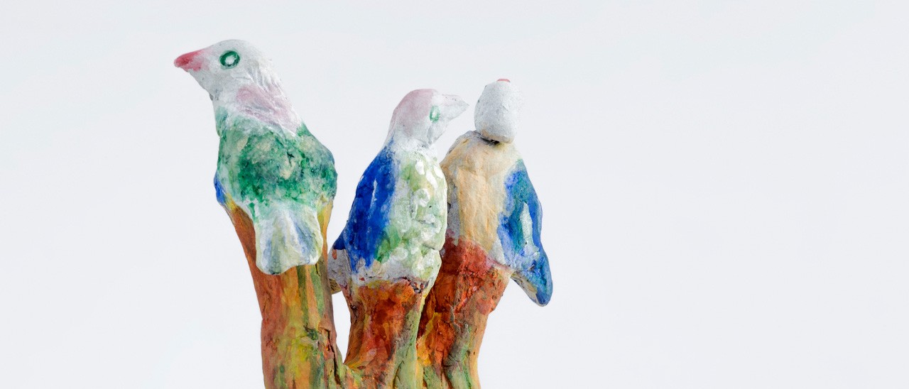 Escultura colorida de tres palomas